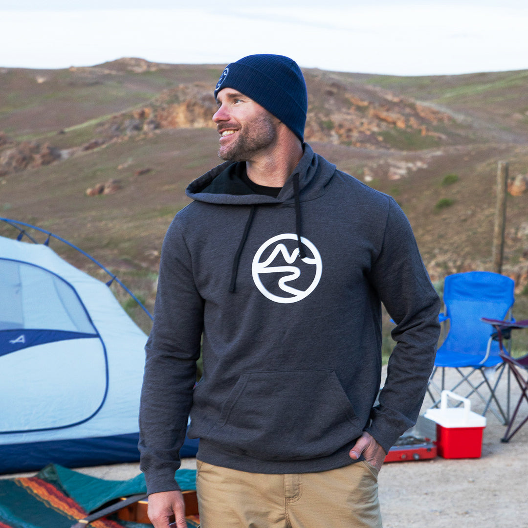 Smiling man wearing dark gray hoodie sweater with black interior and white Mtn Flo logo on chest